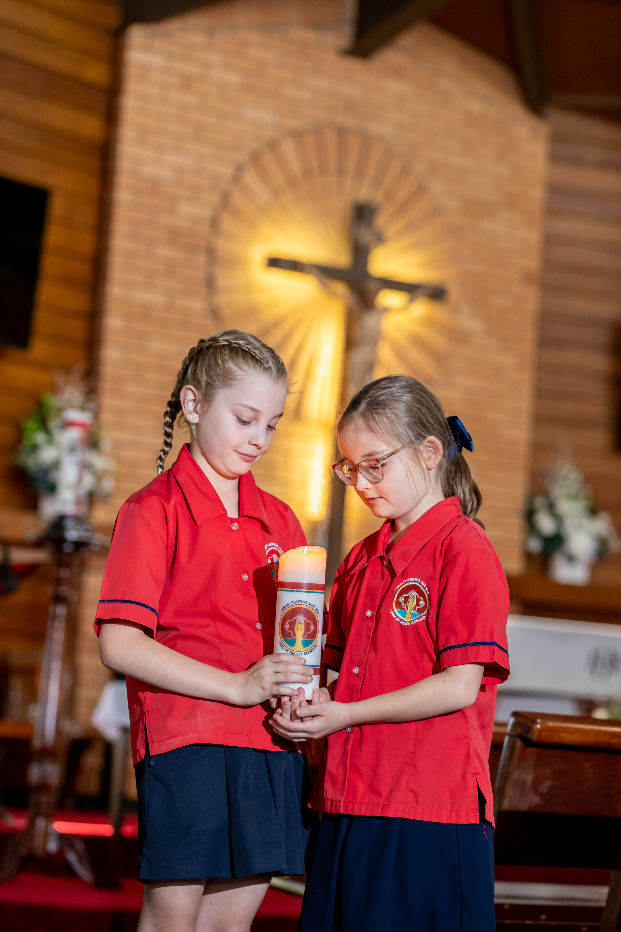 Students holding a candle during a school liturgy representing shared faith traditions spiritual reflection and connection to the Catholic community