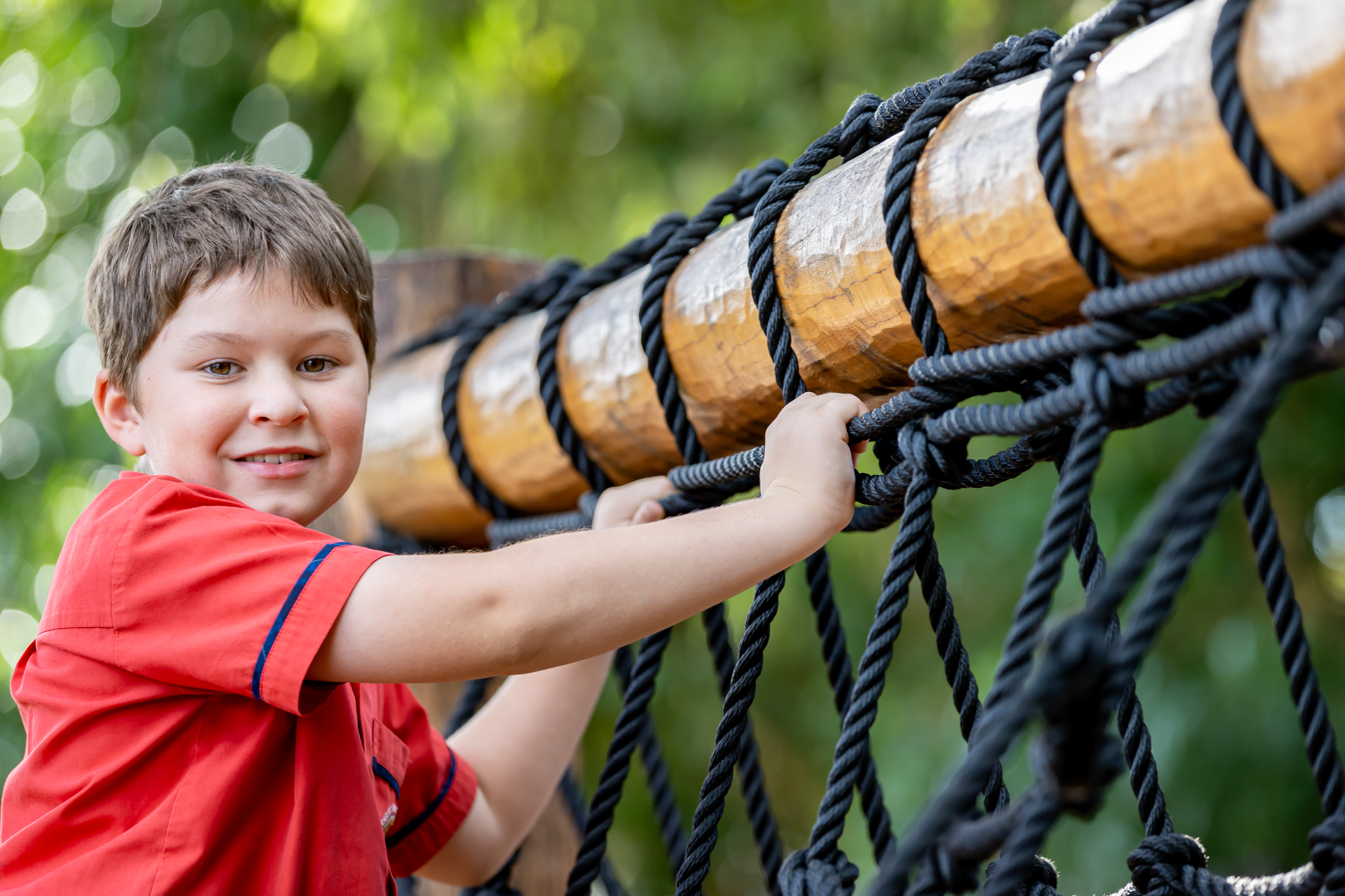 Student engaging in outdoor play on climbing equipment supporting physical development confidence and active learning